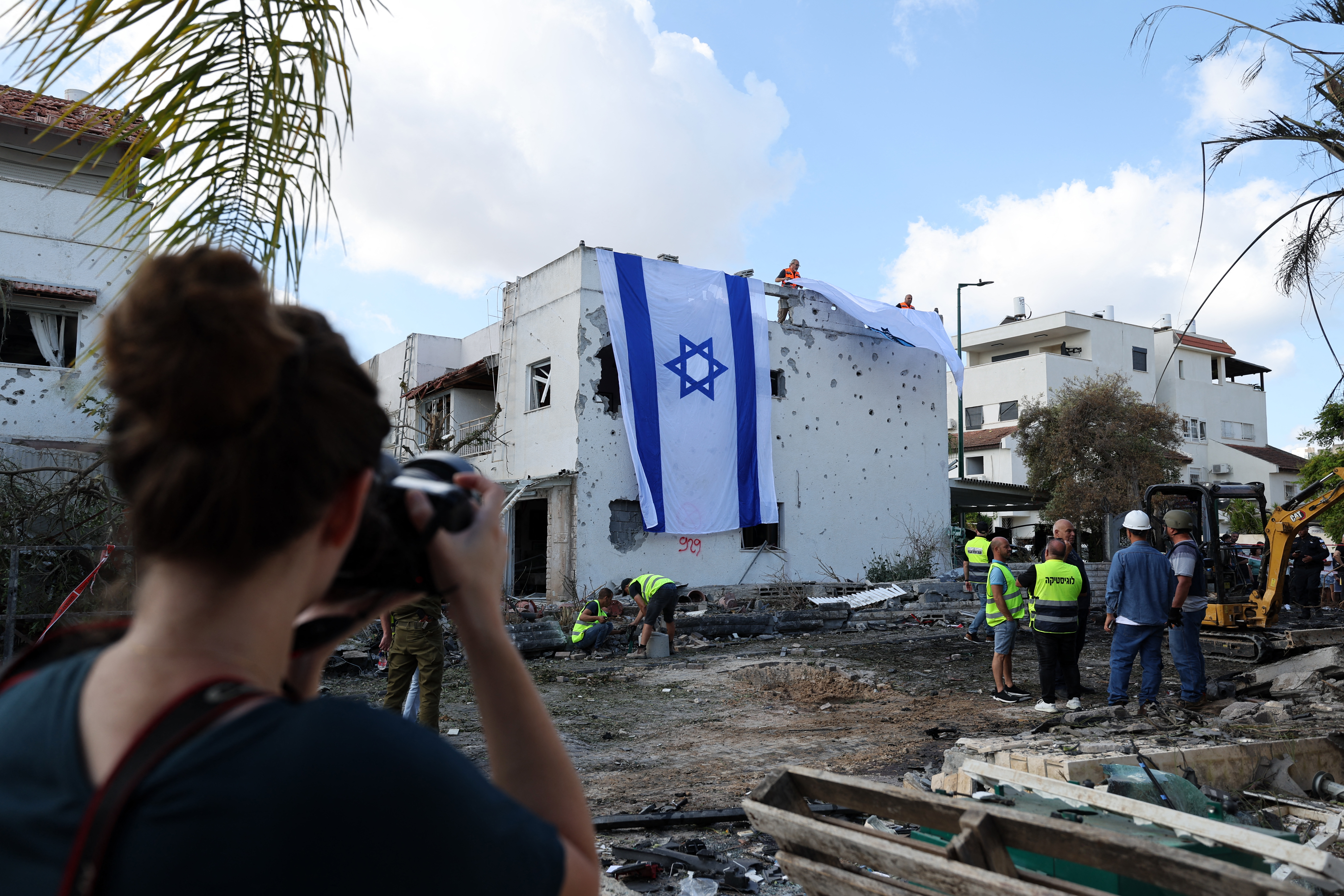 A woman takes a photograph of an Israeli flag deployed on the wall of a damaged building in Kiryat Bialik in the Haifa district of Israel, following a reported strike by Lebanon's Hezbollah on September 22, 2024. (AFP)