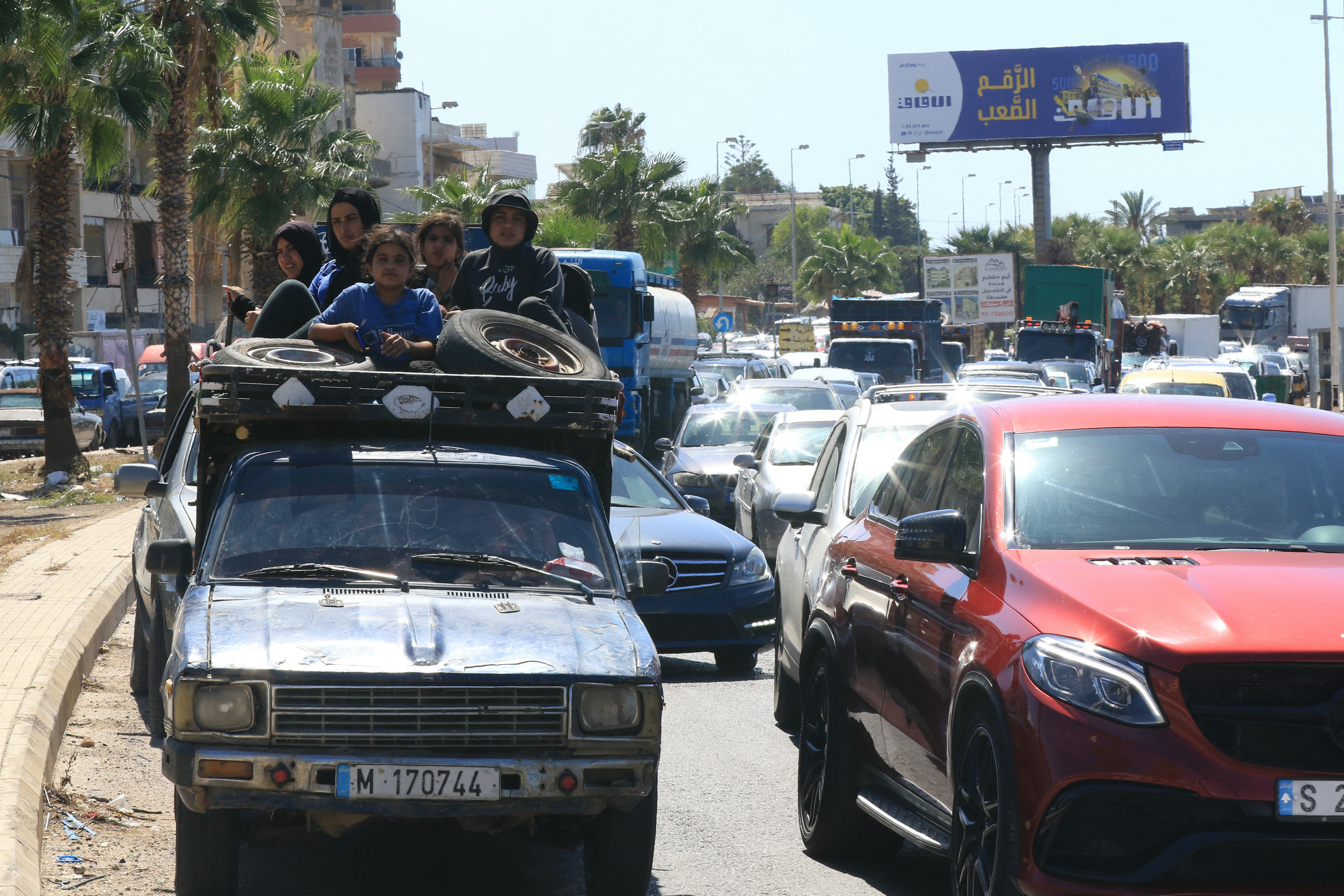 An Arab family sit with their belongings in the back of a truck as they wait in a traffic jam in the southern Lebanese city of Sidon on September 23, 2024. The Israeli military has vowed to carry out more "extensive and precise" strikes against Lebanon. (AFP)