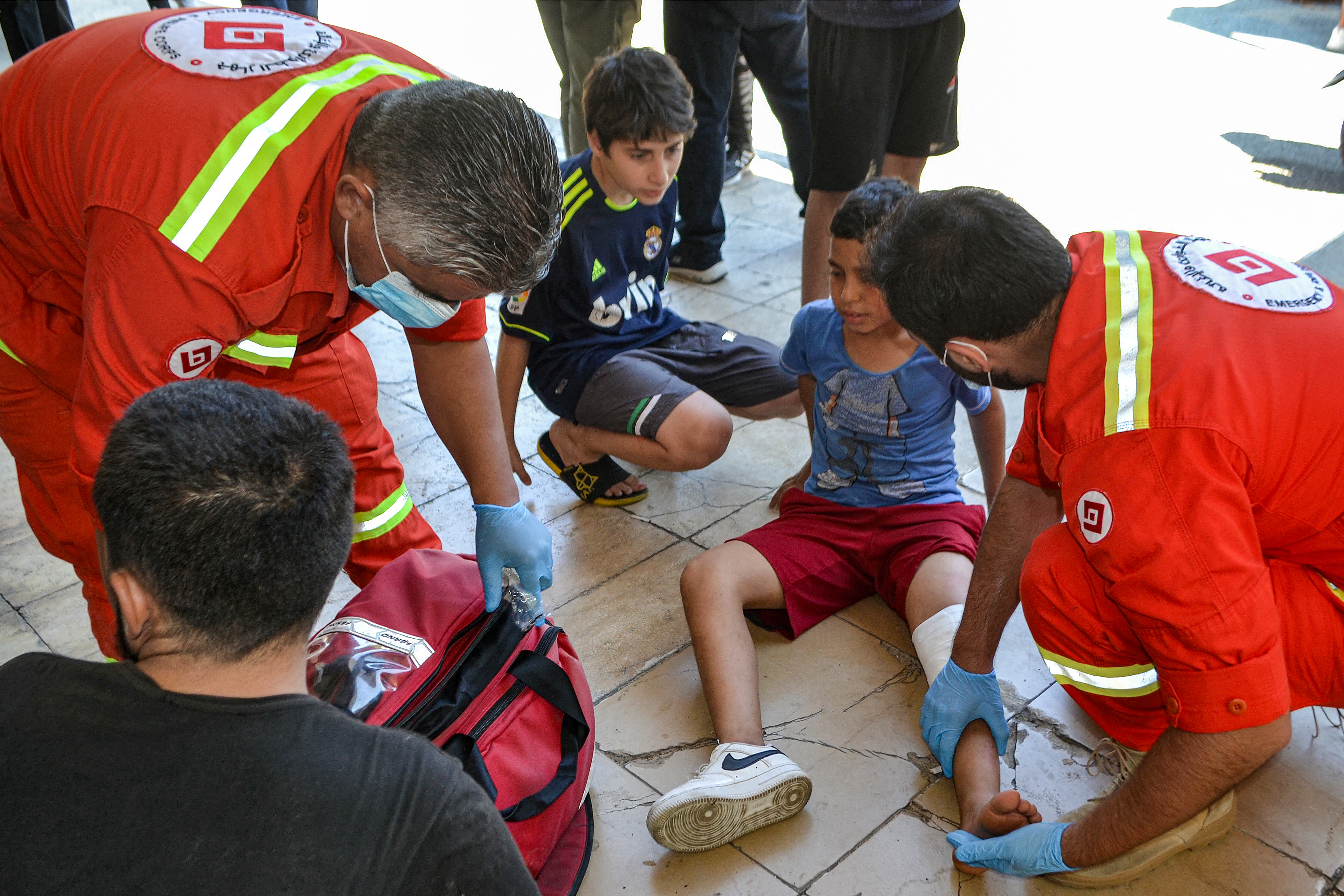 Paramedics attend to a child with an injured leg at a temporary reception shelter for people displaced by conflict, in Lebanon's northern city of Tripoli on September 25, 2024. (AFP)