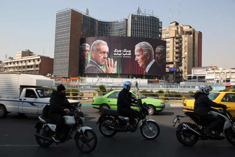 Commuters drive past a billboard bearing pictures of Iran's President Masoud Pezeshkian (second left), armed forces chief of staff Major General Mohammad Bagheri (left) US President Joe Biden and Israeli Prime Minister Benjamin Netanyahu (R) in Vali-Asr square in Tehran on October 27, 2024. Residents of Tehran awoke and went about their business as planned on October 26 after their sleep was troubled by Israeli strikes that triggered blasts that echoed across the city. (AFP)