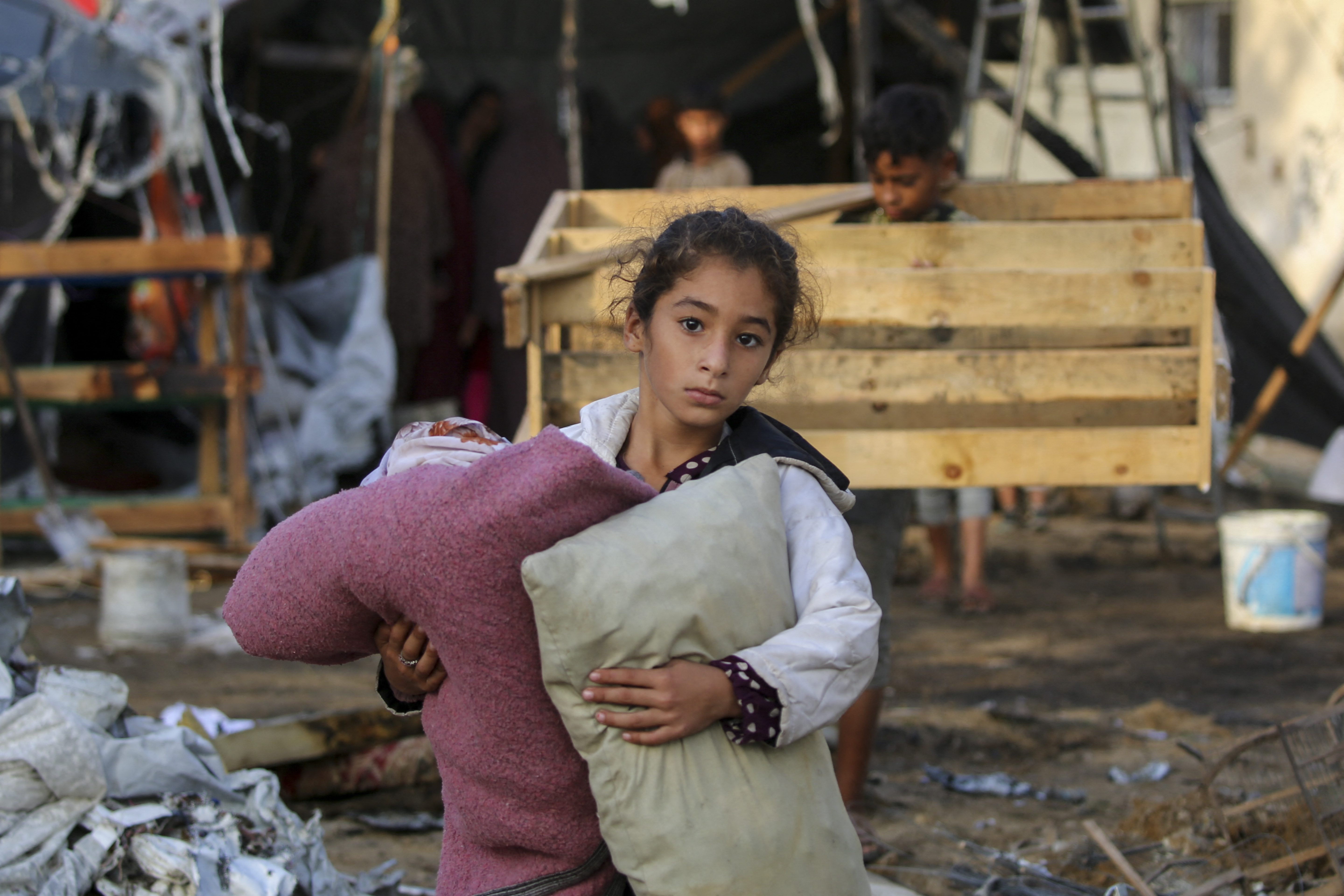 A child carries salvaged items following an Israeli air strike the previous night on the Bureij refugee camp in the central Gaza Strip on October 8, 2024, amid the continuing war between Israel and the Palestinian militant group Hamas. (AFP)