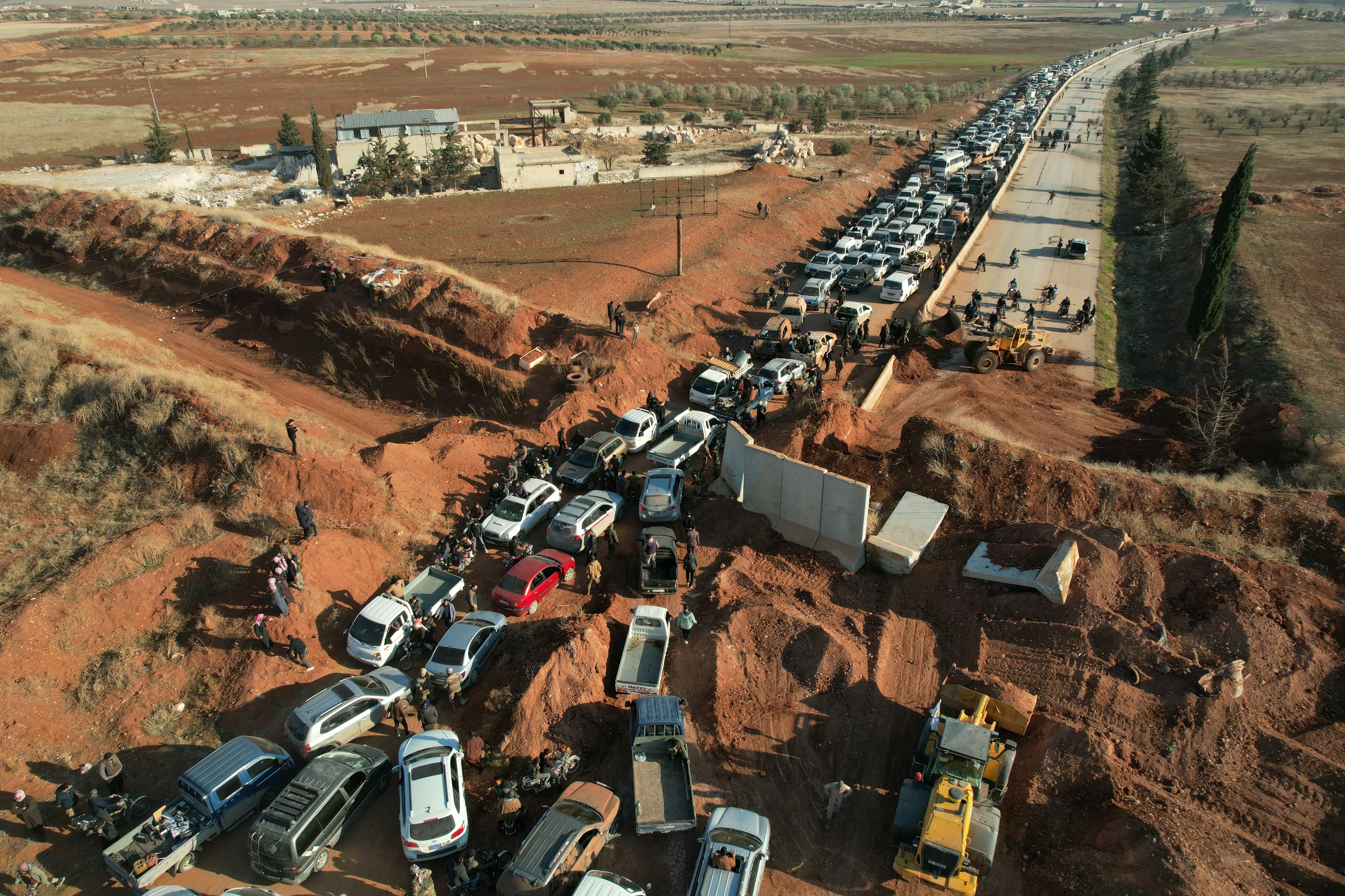 An aerial view shows people crossing an anti-government checkpoint as return to the town of Saraqib in the eastern part of the Idlib province in northwestern Syria on Sunday. (AFP)